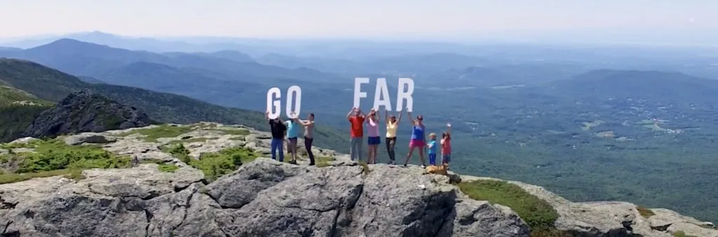 People on top of a mountain with the words "Go Far"