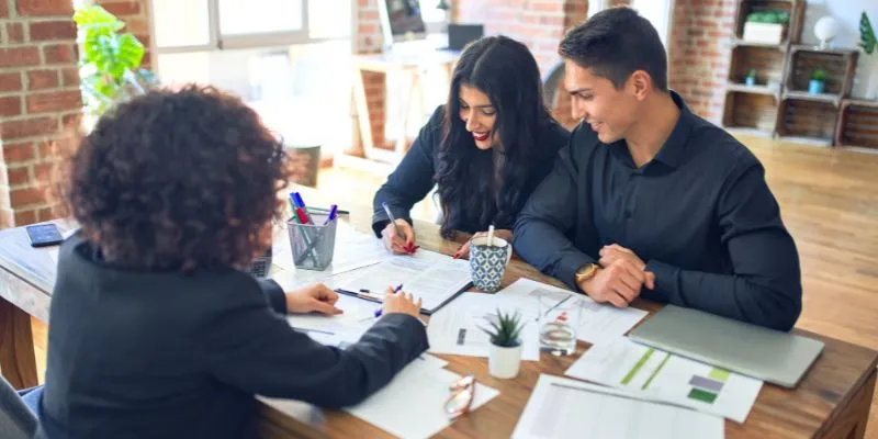 2 business owners signing documents with a bank